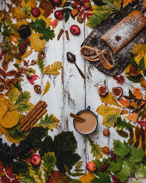 Top view of fresh baked strudel with cup of coffee on wooden background with autumn leaves, figs and apples  - Foto, immagini