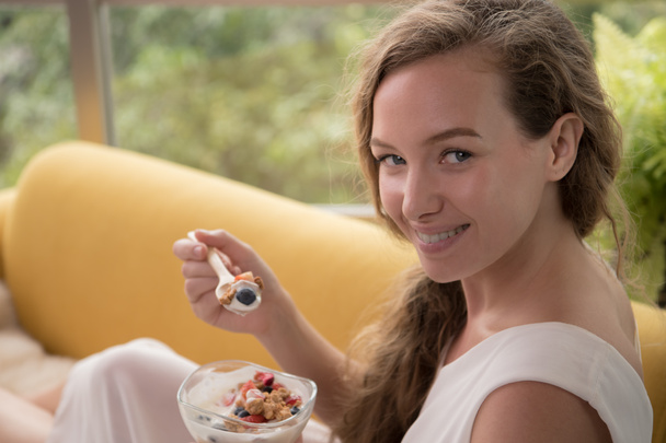gesunde junge Frau auf einer Couch liegend mit einer Schale Joghurt, die entspannt und bequem aussieht - Foto, Bild