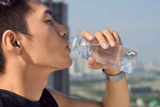 primer plano de un hombre bebiendo agua de una botella afuera
 - Foto, imagen