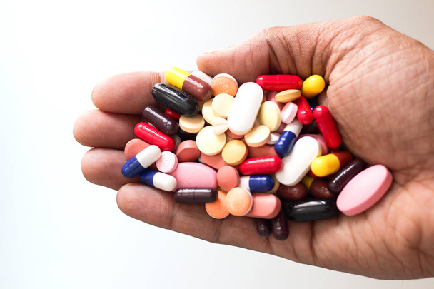 Stapel von Medikamententabletten Kapseln in einer Handfläche vor weißem Hintergrund - Foto, Bild
