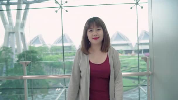 Portret van vrolijke casual gelukkig jonge Aziatische vrouw in de internationale luchthaven glimlachen naar de camera tijdens uw verblijf in terminal. Vrouw gelukkig in het concept van de luchthaven. - Video