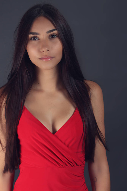 mooie jonge vrouw draagt een rode jurk op grijs - Foto, afbeelding
