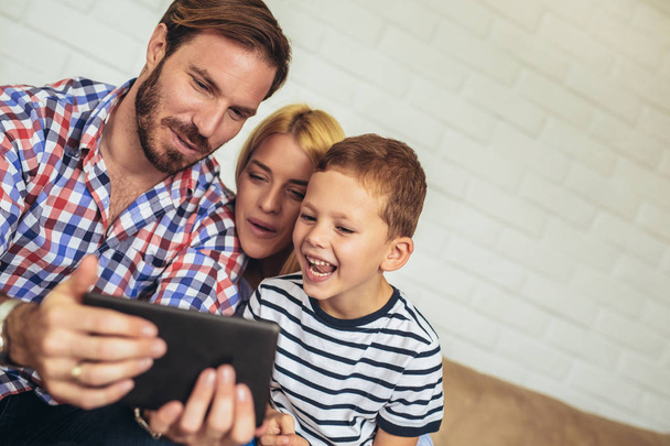 Boldog család használ digitális tábla vevő selfie otthon, és a szórakozás. - Fotó, kép