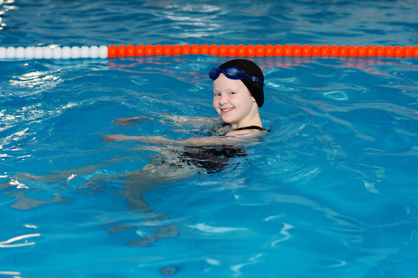 -プールでの子供のためのスイミング レッスン美しい色白の少女は、水に泳ぐ - 写真・画像