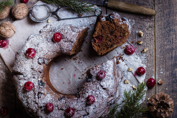 Vakantie dessert. Traditionele zelfgemaakte kerst chocolade cake met een kers op houten tafel achtergrond met feestelijke decoratie. Rustieke stijl. Bovenaanzicht - Foto, afbeelding