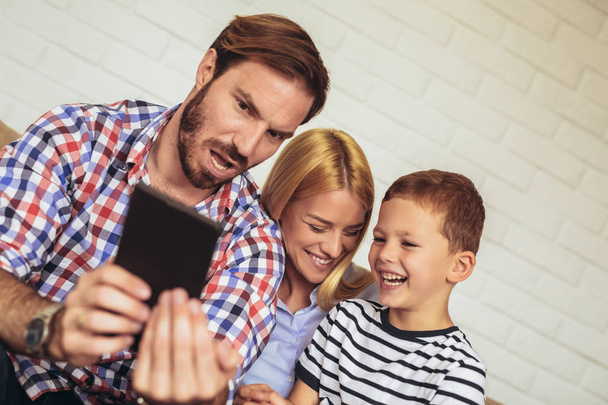 Щаслива сім'я, використовуючи цифровий планшет, беручи селфі вдома, і отримуючи задоволення
. - Фото, зображення