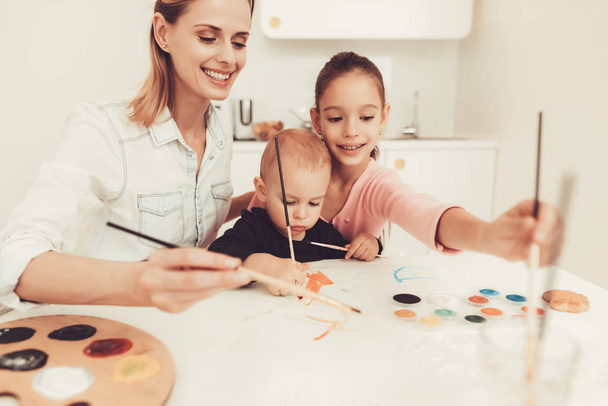 Mom And Daughter Are Drawing With Little Baby. Family Relationship Concept. Sheet And Tassel. Writing With Watercolor. Little Hands. Active Family. Holiday Leisure. Happy Childhood. Parent's Duty. - Фото, изображение