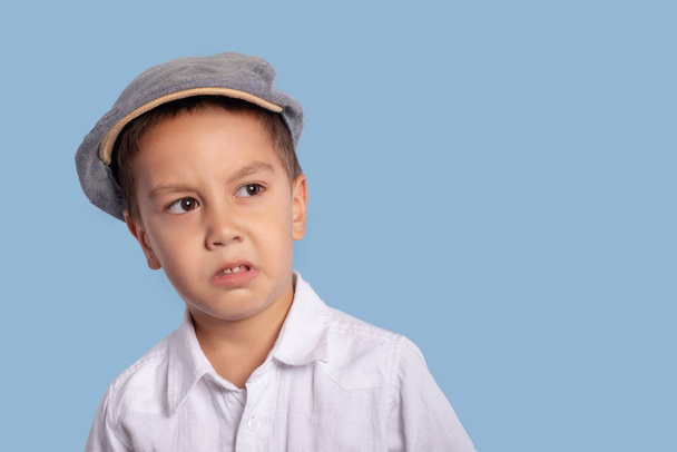 Primer plano del retrato emocional de un niño pequeño con una gorra con una cara ofendida
 - Foto, Imagen