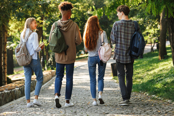 Back view group of young students with backpacks walking at the campus outdoors - Φωτογραφία, εικόνα