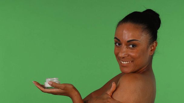 attraktive reife Frau mit Körperlotion auf grünem Hintergrund - Foto, Bild