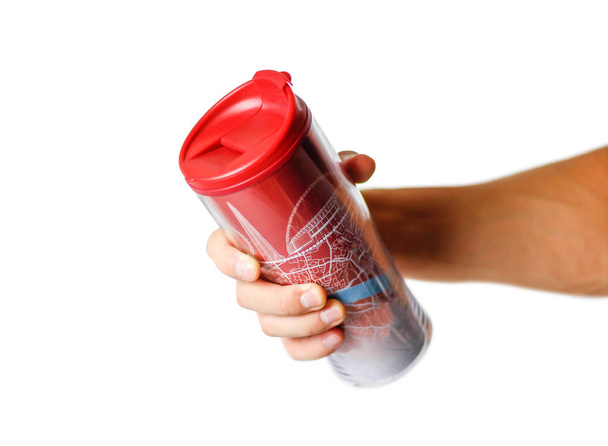 Hand holding a red thermo mug. Close up. Isolated on white background - Φωτογραφία, εικόνα