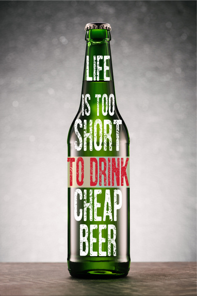 bottiglia di birra su tavolo su sfondo grigio con ispirazione "la vita è troppo breve per bere birra a buon mercato"
  - Foto, immagini