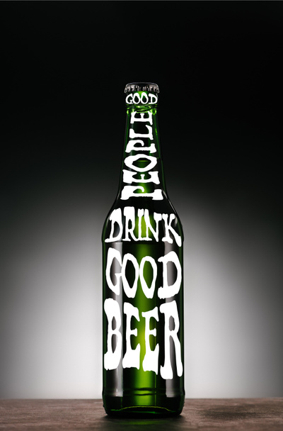 flesje bier op donkere grijze achtergrond met "goede mensen drinken goed bier" inspiratie - Foto, afbeelding