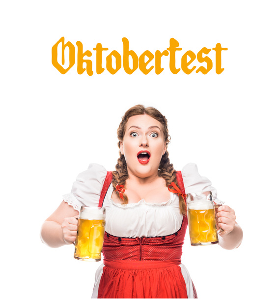 shocked waitress in traditional bavarian dress with mugs of light beer isolated on white background with "oktoberfest" lettering - Photo, Image