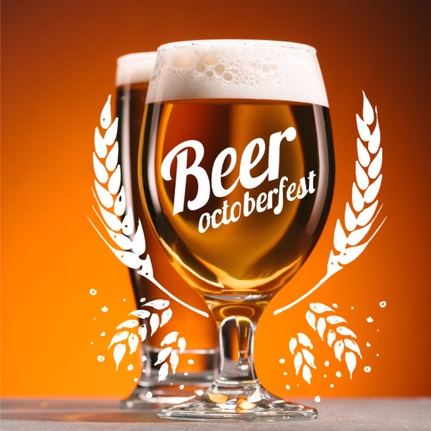 selective focus of arrangement of glasses of beer with froth on orange backdrop with "beer octoberfest" lettering with wheat ears - Photo, image