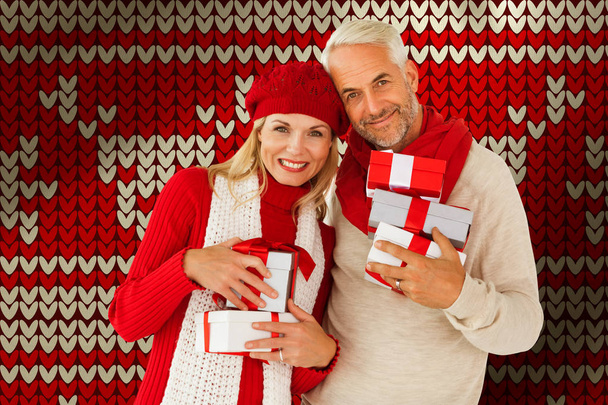Happy festive couple with gifts against red seamless knitted pattern - Foto, immagini