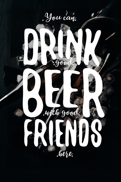 flat lay com balde, garrafas de vidro de cerveja e cubos de gelo dispostos em mesa escura com inspiração "você pode beber boa cerveja com bons amigos aqui"
 - Foto, Imagem