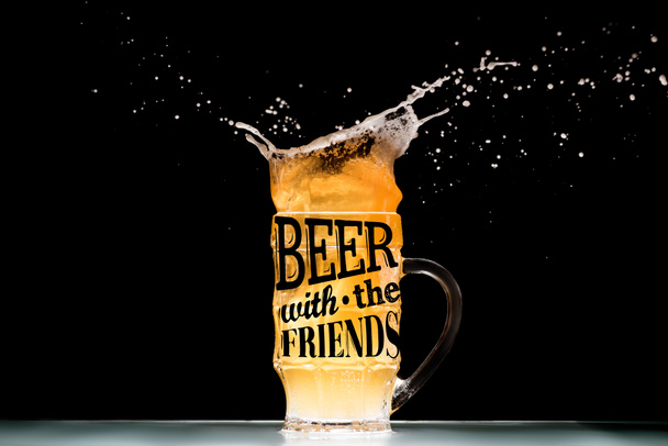 kubek lekkie piwo z pianką i plamy przy stole na czarnym tle z inspiracji "piwo z przyjaciółmi" - Zdjęcie, obraz