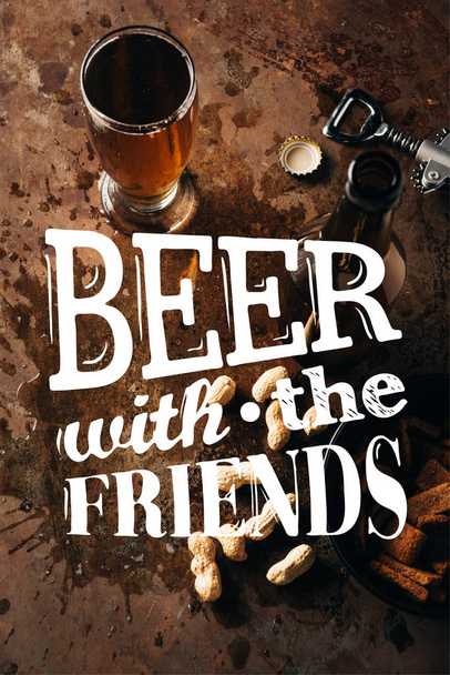 το Top view τοποθετημένα φιστίκια, αρτοπαρασκευάσματα, μπουκάλι και ποτήρι της μπύρας σε σκουριά επιτραπέζια με έμπνευση «μπύρα με τους φίλους» - Φωτογραφία, εικόνα