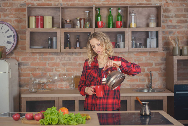 Woman brewing tea in the kitchen - Foto, Imagen