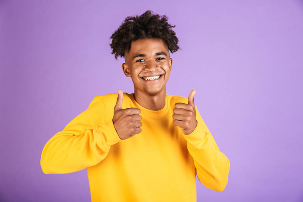 Portrait of a smiling young afro american man dressed in sweatshirt showing thumbs up isolated - Valokuva, kuva