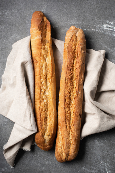 bovenaanzicht van stokbrood op linnen op grijs tafelblad - Foto, afbeelding