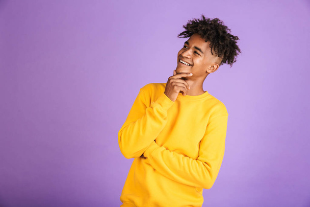 Portrait of a smiling young afro american man dressed in sweatshirt looking away at copy space isolated - Fotografie, Obrázek