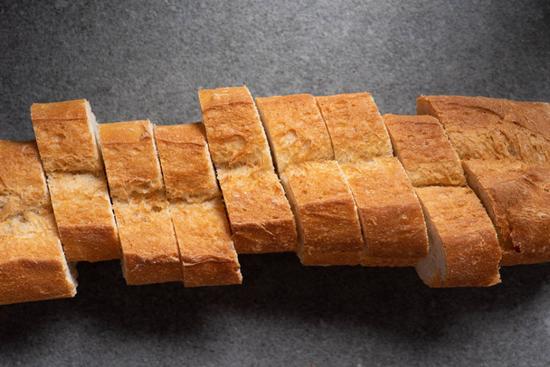 bovenaanzicht van gesneden stokbrood op grijze oppervlak - Foto, afbeelding