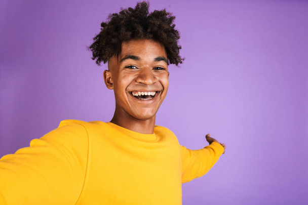 Portrait of a cheerful young afro american man dressed in sweatshirt taking a selfie isolated - Photo, image