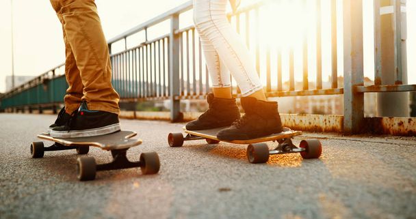 Young attractive couple riding skateboards and having fun together - Zdjęcie, obraz