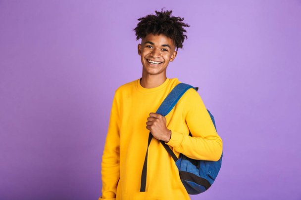 Portrait of a cheerful young afro american man dressed in sweatshirt carrying backpack isolated - Fotografie, Obrázek