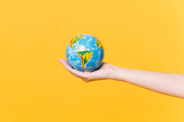 Close up female hold on hand palm Earth world globe isolated on yellow background. Air flight journey. Stop nature garbage, ecology environment protection concept. Save planet. Copy space advertising - Zdjęcie, obraz