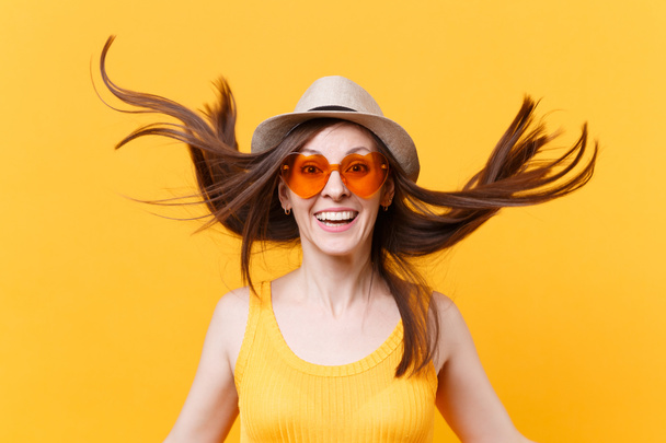Ritratto di giovane donna sorridente eccitata in cappello estivo di paglia, occhiali arancioni con spazio di copia dei capelli svolazzante isolato su sfondo giallo. Persone emozioni sincere, concetto di stile di vita. Area pubblicitaria
 - Foto, immagini
