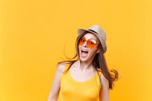 Retrato de jovem sorridente animado em chapéu de verão de palha, óculos laranja com espaço de cópia de cabelo oscilante isolado no fundo amarelo. Pessoas emoções sinceras, conceito de estilo de vida. Área publicitária
 - Foto, Imagem