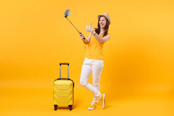 Na żółtym tle pomarańczowy tle szczęśliwy turysta Kobieta w letnie ubranie, kapelusz, robić selfie zrzut na telefon komórkowy. Pasażera podróżowania za granicą, podróż na weekendy wypad. Koncepcja lot Air - Zdjęcie, obraz