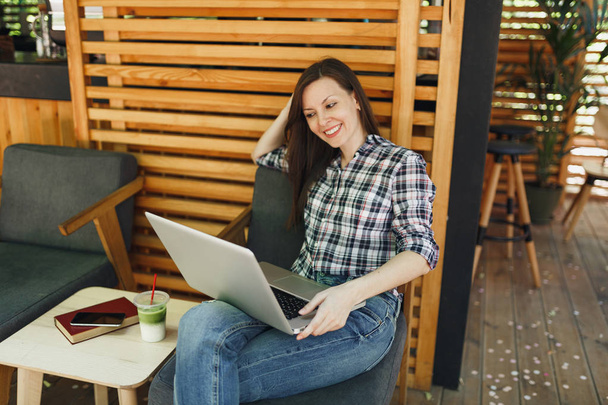 Nainen ulkona Street Summer kahvila puinen kahvila istuu rento vaatteita, työskentelee moderni kannettava tietokone, rentouttava vapaa-ajalla. Liikkuva toimisto. Elämäntapa freelance liiketoiminnan käsite
 - Valokuva, kuva