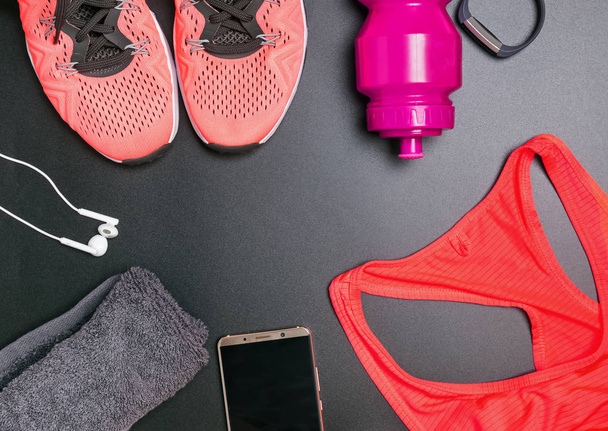 Fitness accessories including sneskers, top, bottle with water on black background - 写真・画像