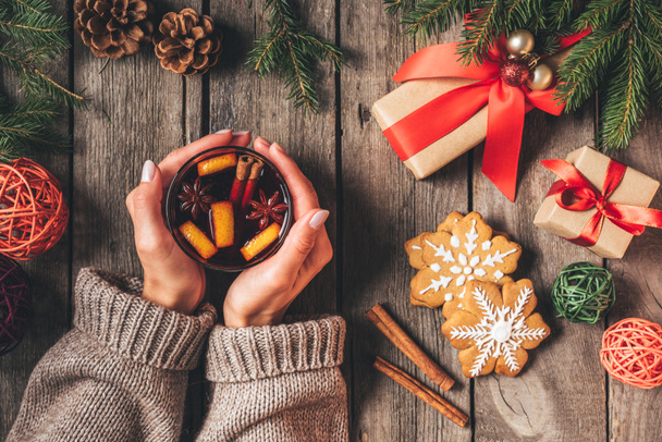 vue recadrée de la femme tenant verre avec du vin chaud chaud chaud sur fond en bois avec des cadeaux de Noël
 - Photo, image