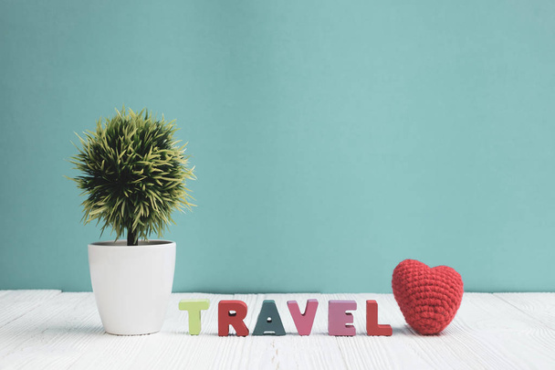 TRAVEL letters text and notebook paper and little decoration tree in white vase on wooden background, travel vacation concept idea. - Фото, изображение