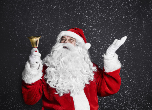 Санта-Клаус с колокольчиком среди снега
  - Фото, изображение
