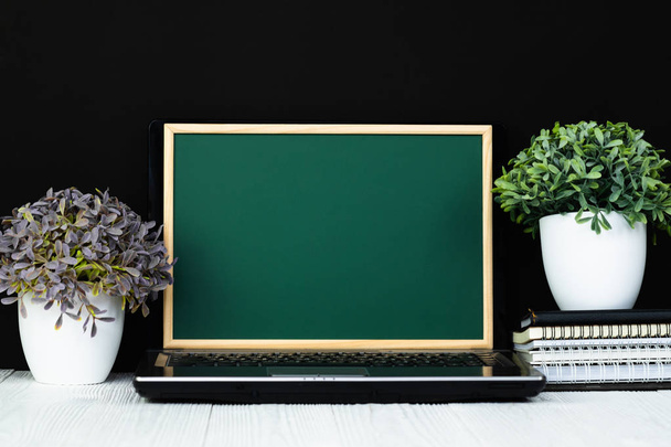 Notebook laptop computer with green chalkboard screen and pile of notebook paper stationery or school supplies. Back to school and education concept idea. - Foto, afbeelding