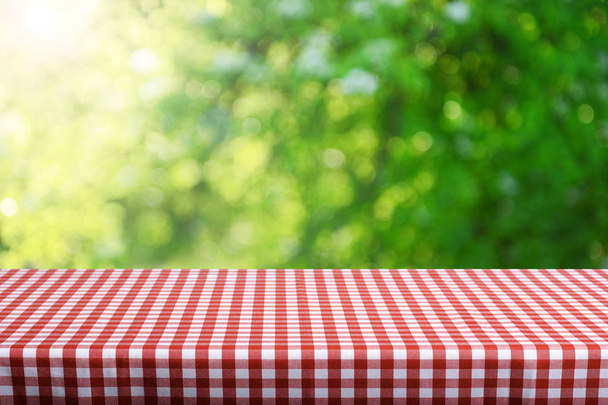 Empty table with checkered tablecloth and blurred natural background - Photo, Image