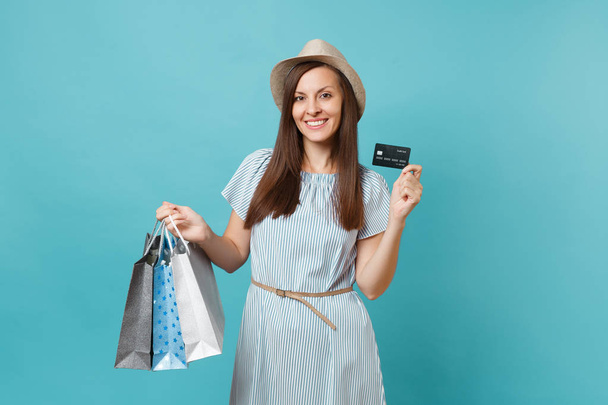 Портрет красивой кавказской женщины в летнем платье, соломенная шляпа, держащая пакеты с покупками после покупок, банковская кредитная карта изолирована на голубом пастельном фоне. Копирование места для рекламы
 - Фото, изображение