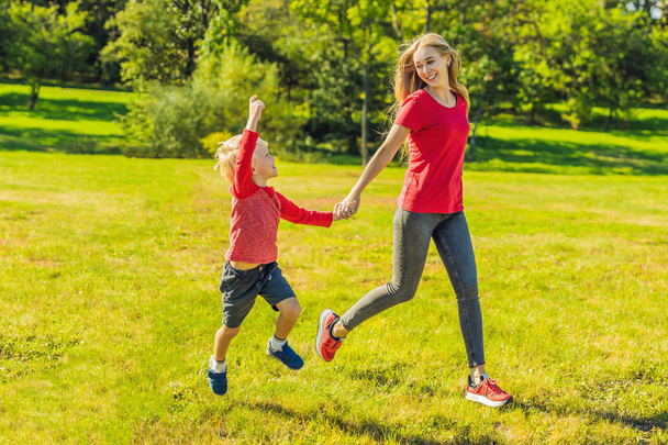 Mom and son running on green grass in park - Fotoğraf, Görsel