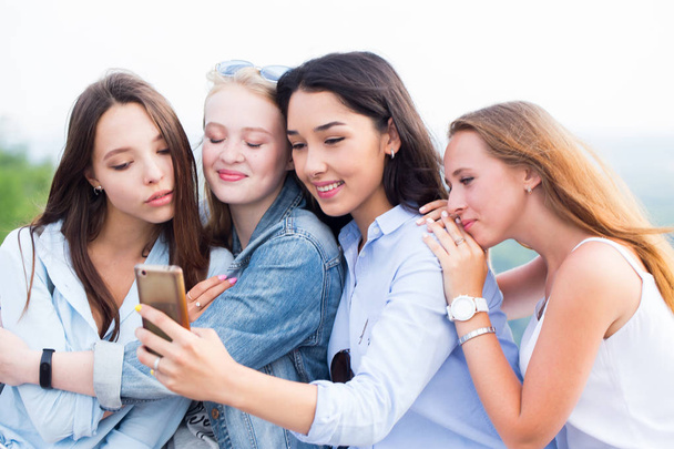 Close up of four beautiful young female students doing selfies and smiling on the background of nature - Fotoğraf, Görsel