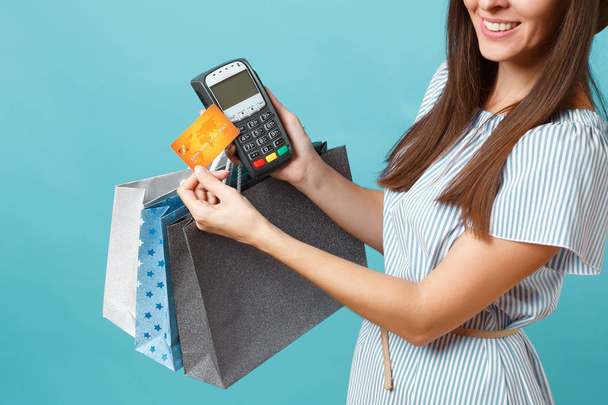 Porträt Frau in Kleid, Hut mit Paketen Taschen mit Einkäufen nach dem Einkauf, drahtlose moderne Bank-Zahlungsterminal, um Kreditkartenzahlungen zu verarbeiten und zu erwerben isoliert auf blauem Pastellhintergrund - Foto, Bild
