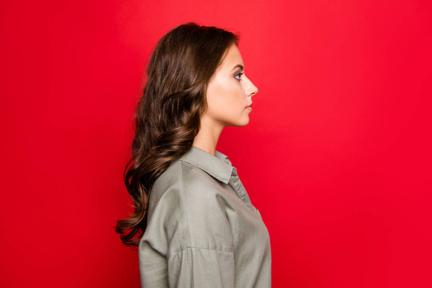 Profile side view portrait of focused, pretty brunette woman, wearing in blouse isolated on shine red background - Fotografie, Obrázek