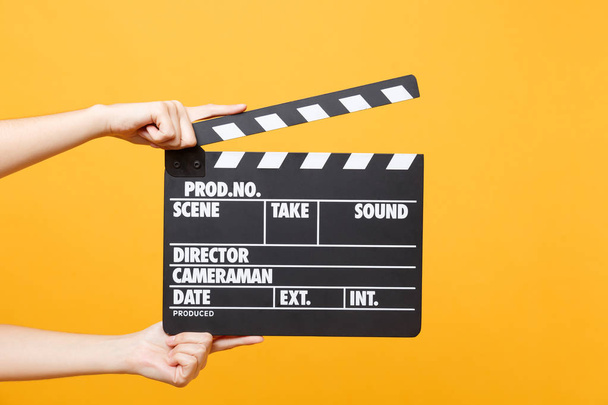 Close up female holding in hand classic director clear empty black film making clapperboard isolated on yellow orange background. Cinematography production concept. Copy space for advertising - Φωτογραφία, εικόνα
