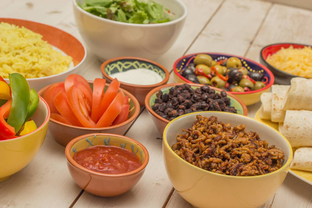 Verschiedene Zutaten für mexikanische Burritos mit Tortillas, Reis, Paprika, Hackfleisch, Tomaten, Oliven - Foto, Bild