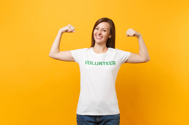 Portret szczęśliwy uśmiechający się zadowolony kobiety w biały t-shirt z pisemnej napis zielony tytuł wolontariusza na białym tle na żółtym tle. Dobrowolne bezpłatnej pomocy pomoc, miłość łaskę pracy koncepcja - Zdjęcie, obraz